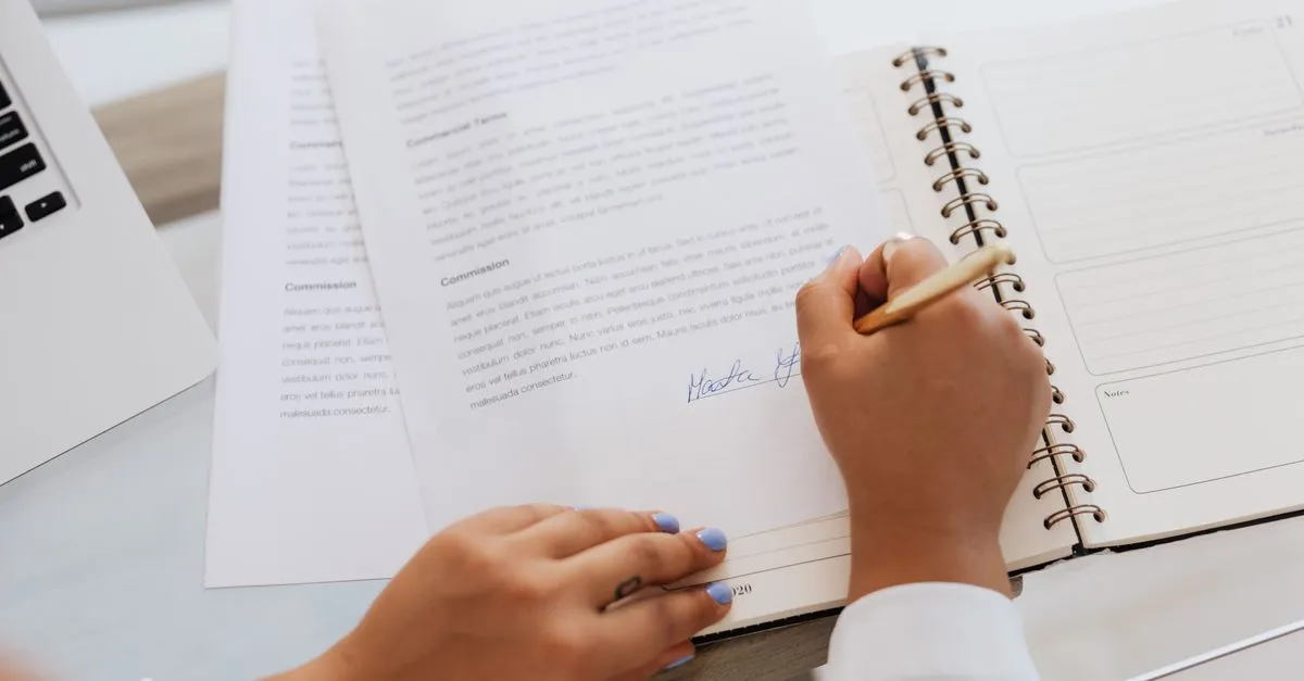 Hand signing a paper document with a pen, the analog version of an online signature