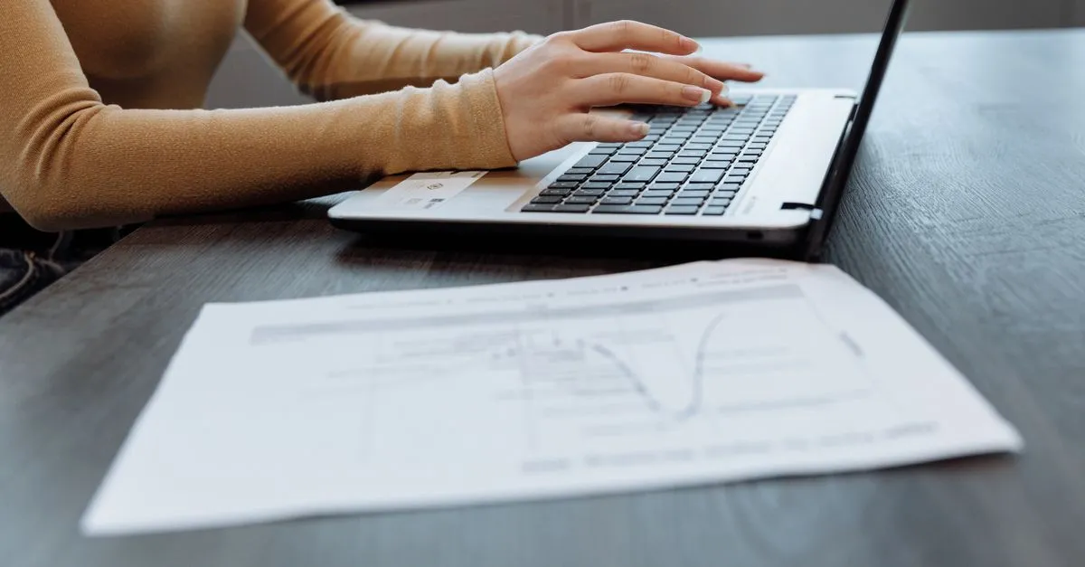 Hands typing on a laptop with a document open — cleaning up line breaks in text