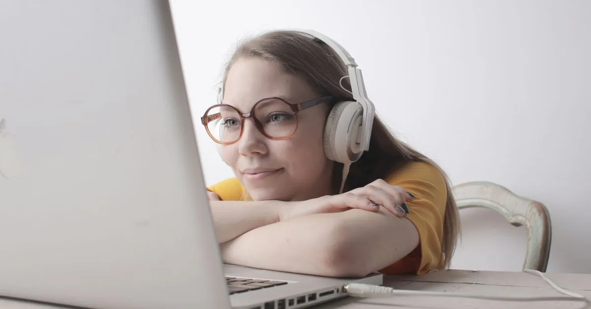 Person wearing headphones listening to text read aloud on a laptop with a browser text to speech tool