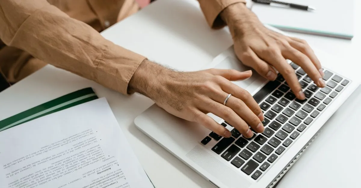 Person typing a Word document on a laptop before converting the .docx file to a PDF